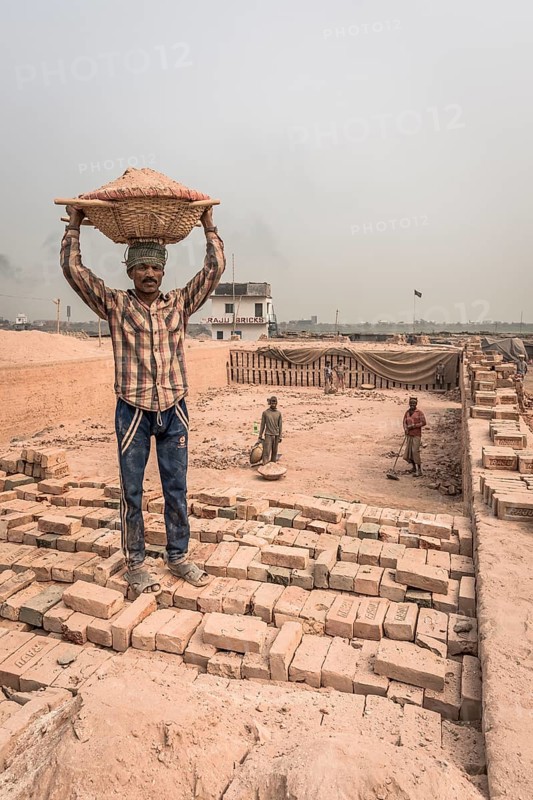Brickyard worker carrying basket of ashes on his head
