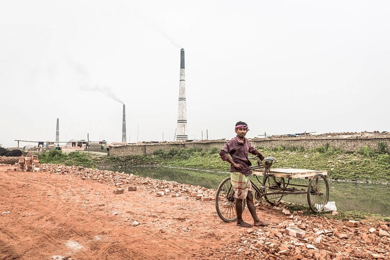 Worker with a rickshaw in front of a brickyard