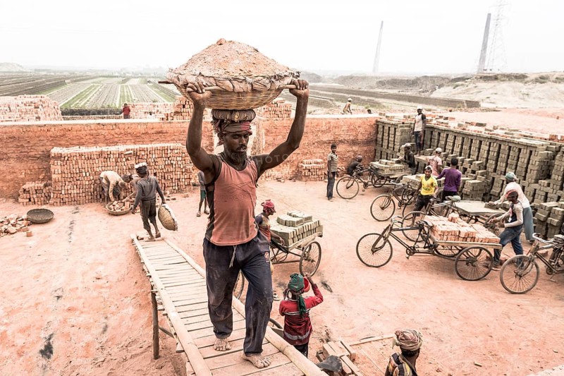 Brickyard worker carrying basket of ashes on his head