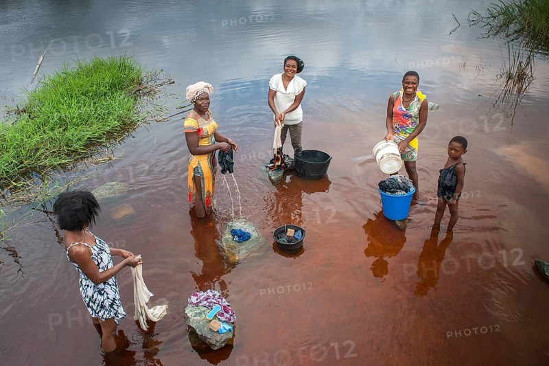 Women washing clothes by the river Ntem in the rainforest
