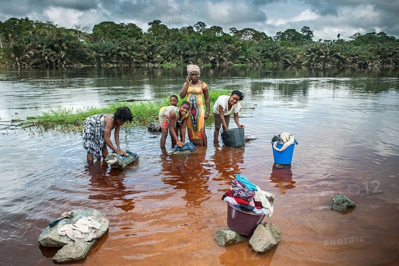 Women washing clothes by the river Ntem in the rainforest