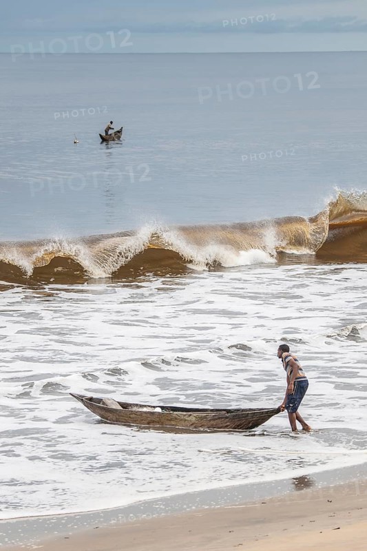 Fisherman with a dugout canoe on the beach