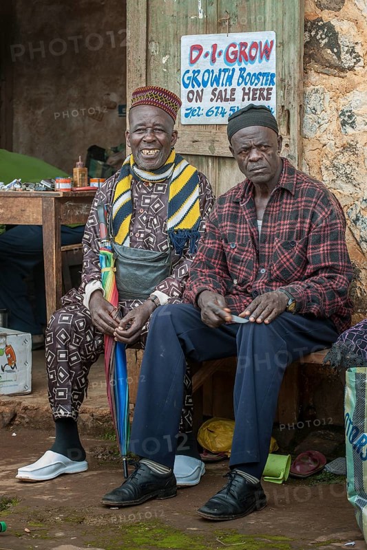Two men sitting on bench at market
