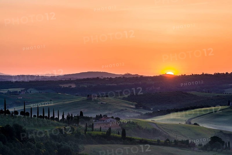 Typical green Tuscan landscape in Val d'Orcia with a farm on a hill