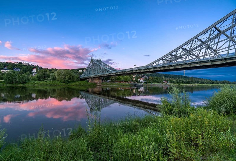 Historical bridge Blaues Wunder is crossing the river Elbe at dust with red cloud above it