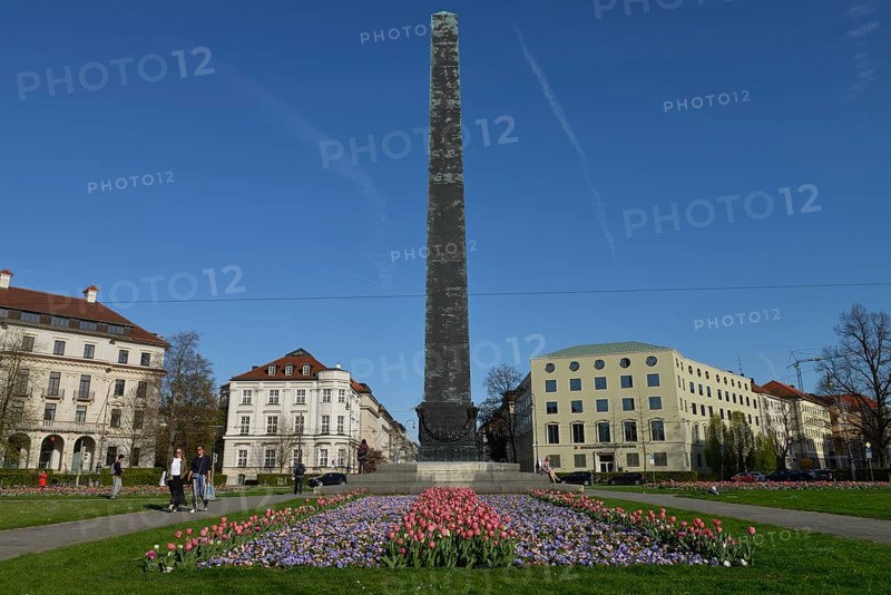 Obelisk with flower beds in front of houses roundabout