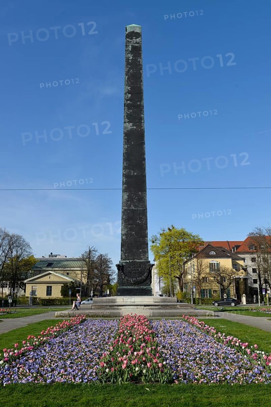 Obelisk with flower bed in front of houses roundabout