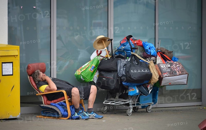 Homeless person with many bags on luggage trolley