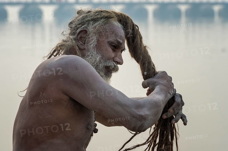 Sadhu drying his dreadlocks on Ganges riverbank