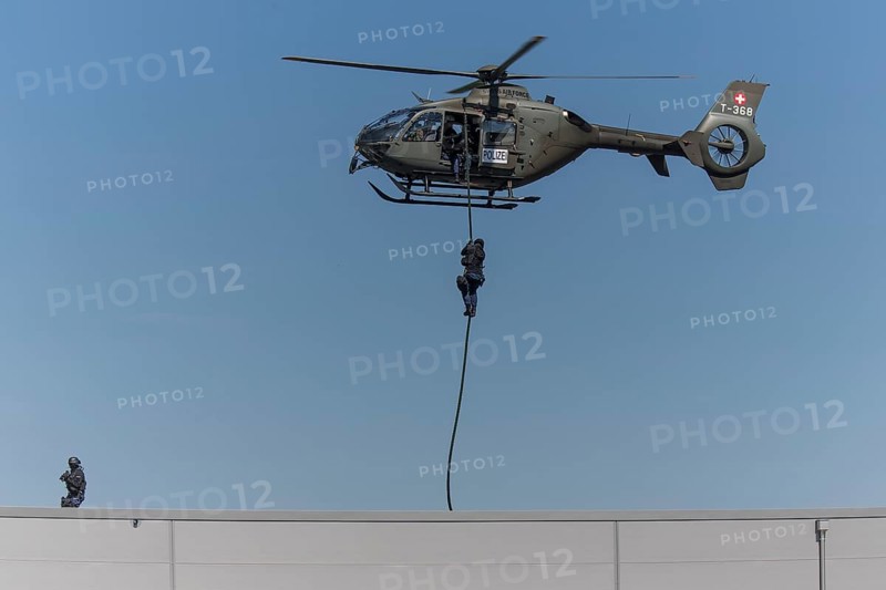 Armed policeman abseiling from helicopter onto roof