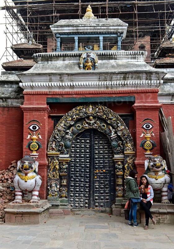 Two Nepalese girls looking at a mobile phone at the gate to Taleju Temple