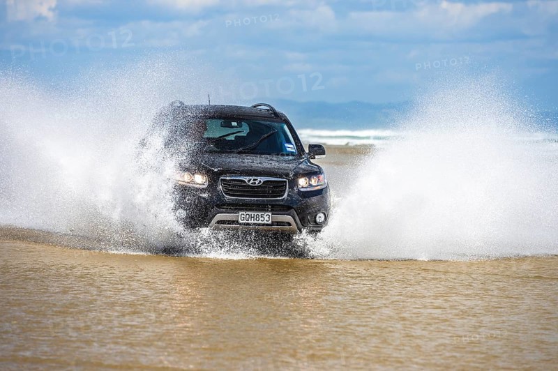 Black Hyundai Santa Fe 4x4 SUV drives on the beach of Ninety Mile Beach in the water