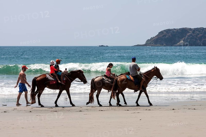 Riders on horseback on the beach Playa Espadilla