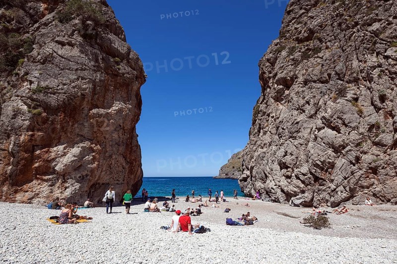 People sunbathe on the beach in the gorge Torrent de Pareis