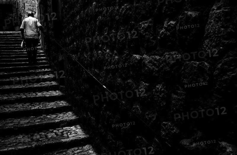 Old man climbs stairs in old town. Fornalutx