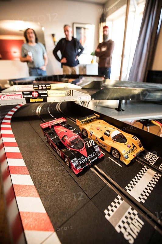 Men playing in the living room with a large Carrera train