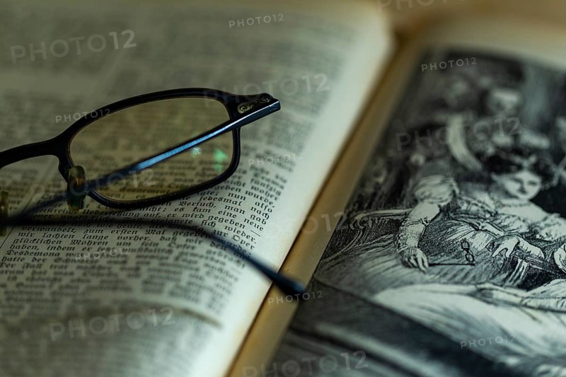 Opened old book with illustration and glasses