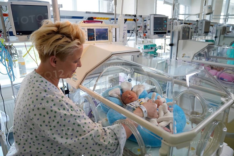 Mother of twins with one of her newborns in an incubator