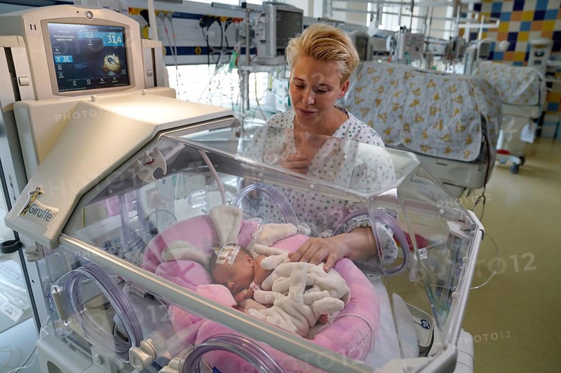 Mother of twins with one of her newborns in an incubator
