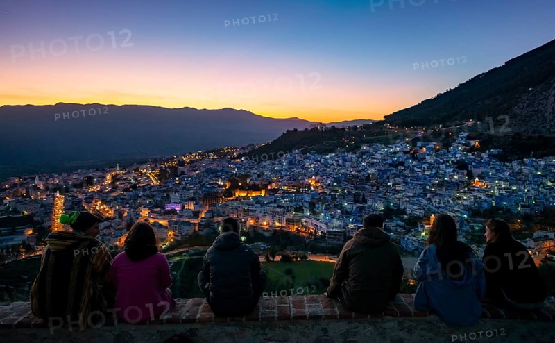 People sitting on a wall overlooking city Chefchaouen