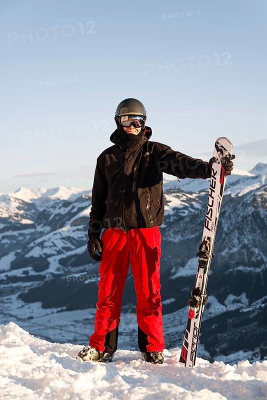 Skier stands at the piste and holds ski