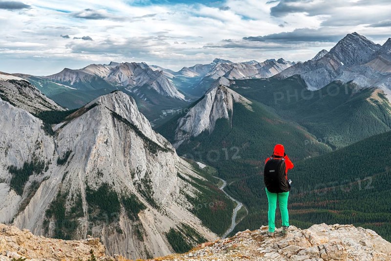 Female hiker views from summit over mountain landscape
