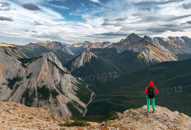 Female hiker looks from summit over mountain landscape
