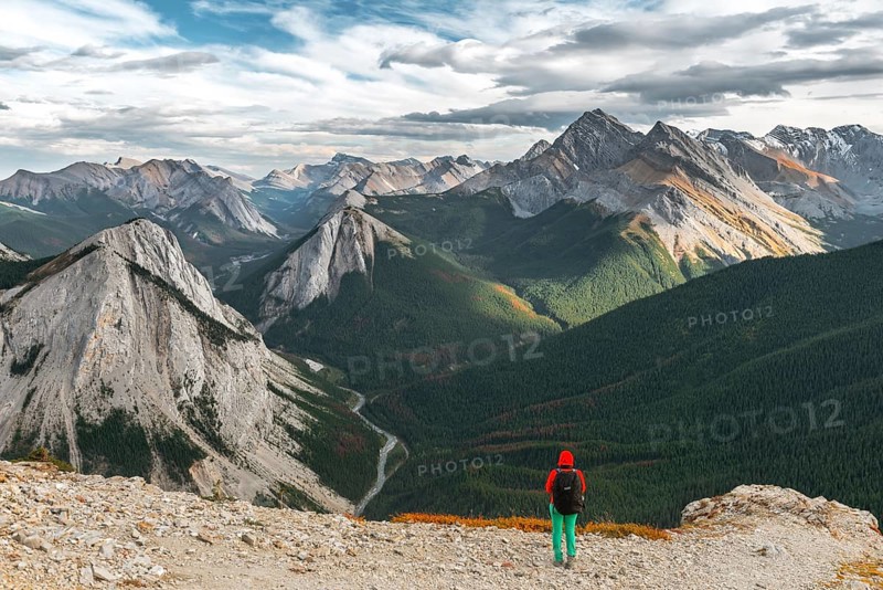 Female hiker views from summit over mountain landscape