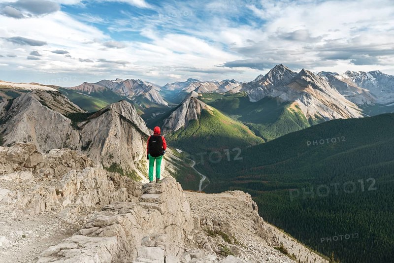 Female hiker views from summit over mountain landscape