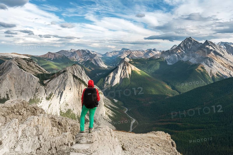 Female hiker views from summit over mountain landscape