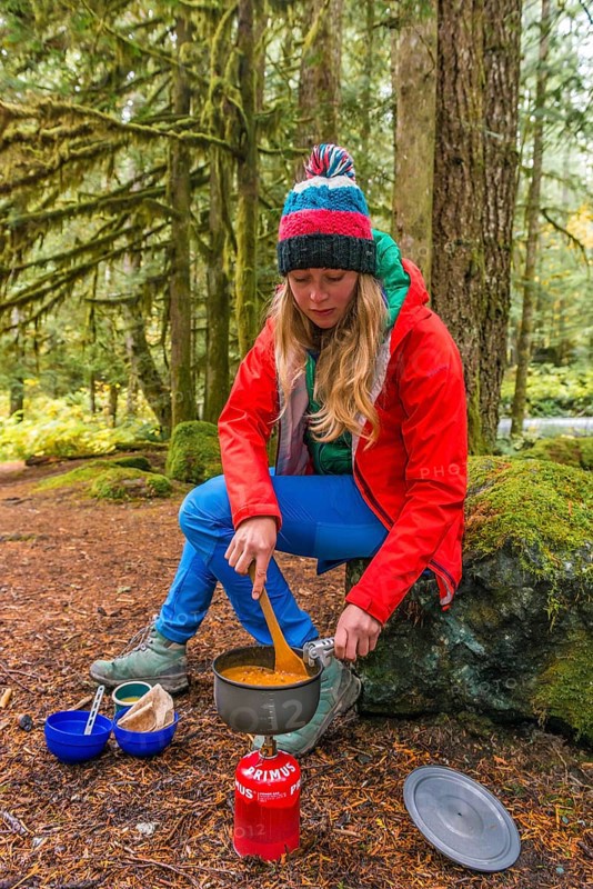 Young woman cooking outdoors with camping stove