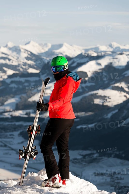 Female skier with ski helmet standing with ski at the ski slope above the valley