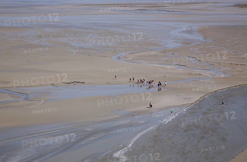 Hikers in mudflat at low tide in Mont Saint Michel