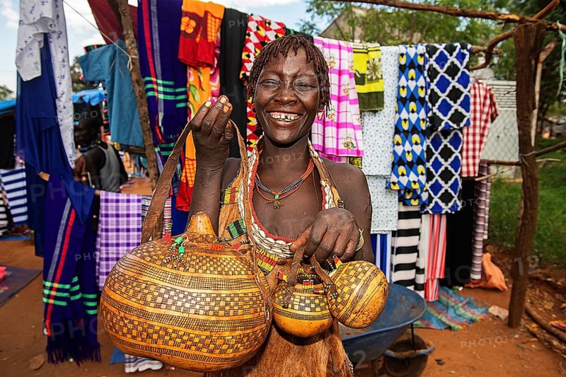 Laughing woman of the Hamer ethnic group sells artfully decorated calabashe pumpkins