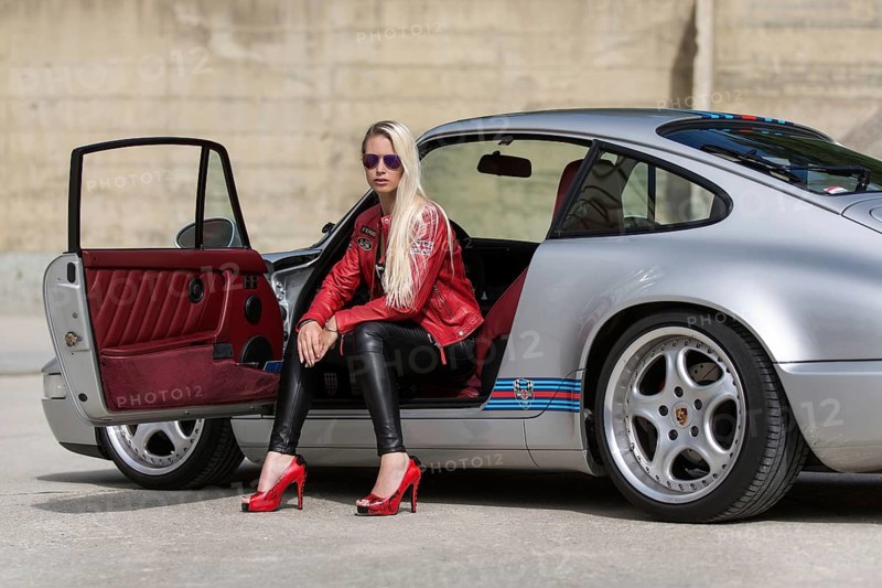 Young woman with long blonde hair poses with Porsche 911 Carrera 4