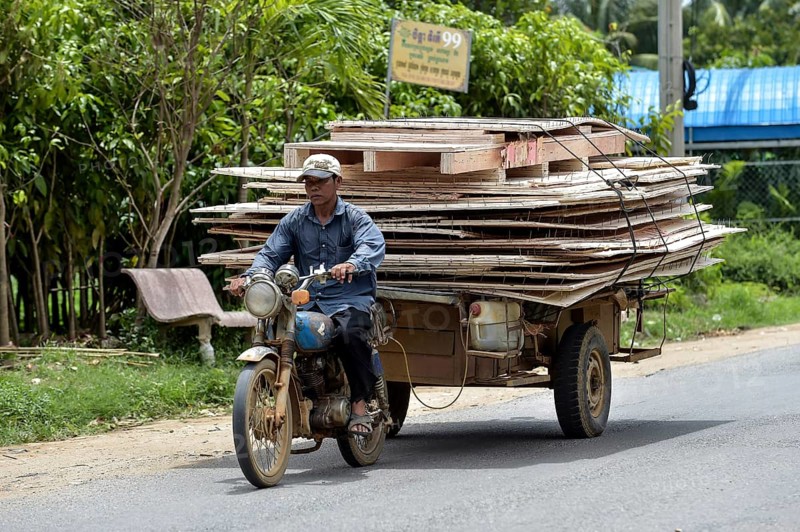 Man with moped and trailer transporting large wooden panels