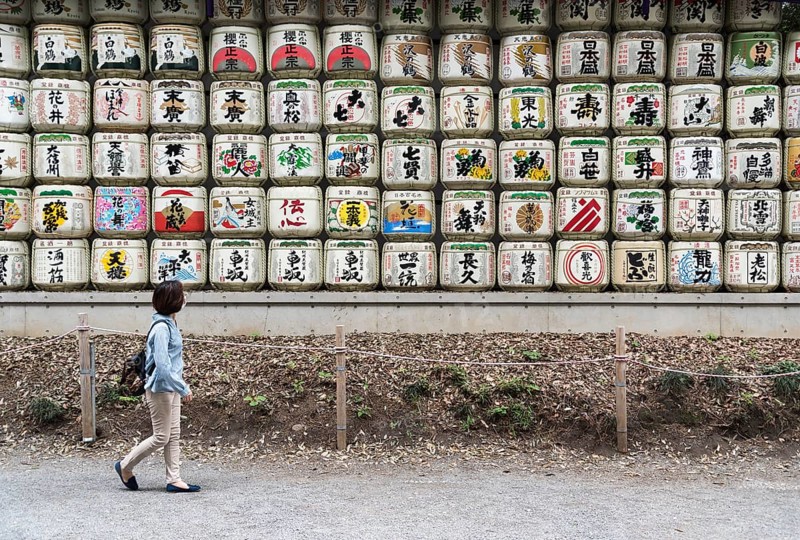 Woman walks pass sake barrels at Meiji Jingu Shrine