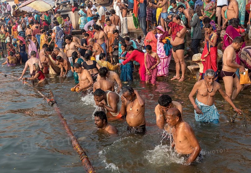 Hindu believers bath and perform ritual bath and puja prayers at ghats in the River Ganges