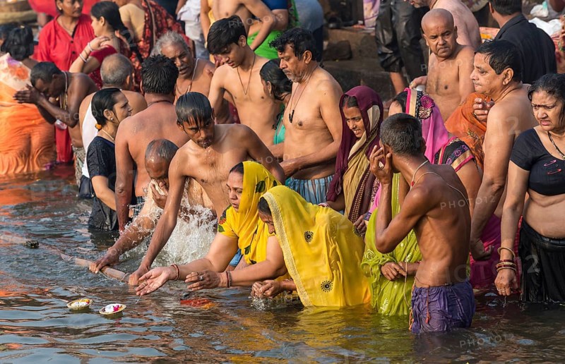 Hindu believers bath and perform ritual bath and puja prayers at ghats in the River Ganges