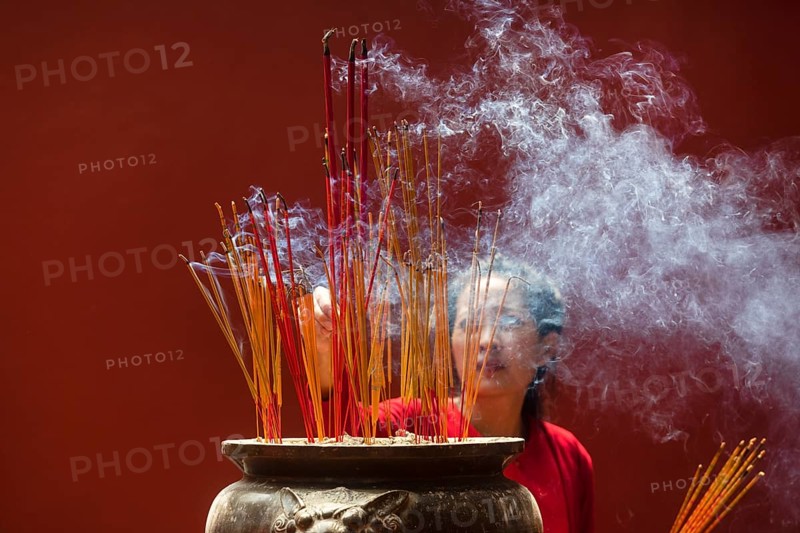 Young woman with burning incense sticks on Chinese New Year
