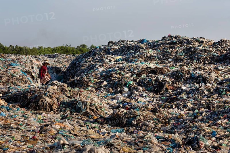 Garbage collector in garbage dump with plastic garbage