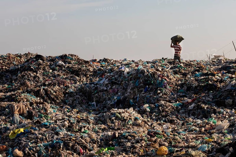 Garbage collector in garbage dump with plastic garbage