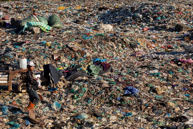 Garbage collector in garbage dump with plastic garbage