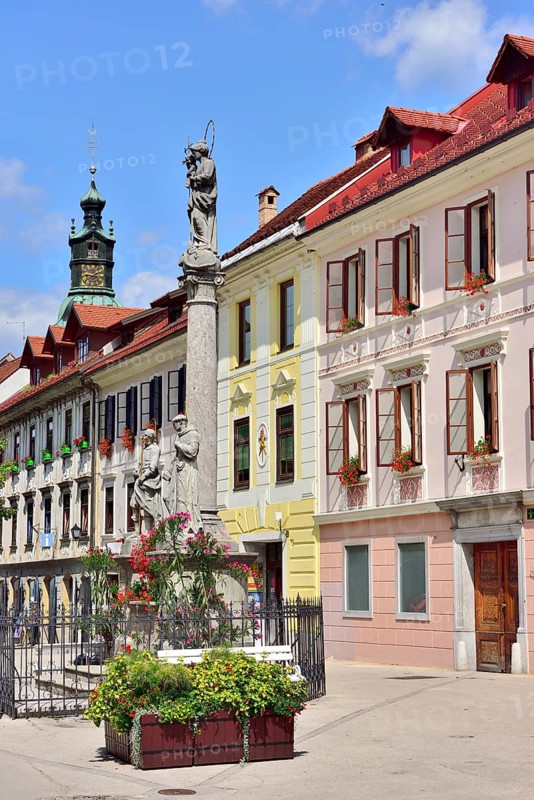 Nepomuk fountain in front of house facades on market square Mestni Trg with tower St. James' Church