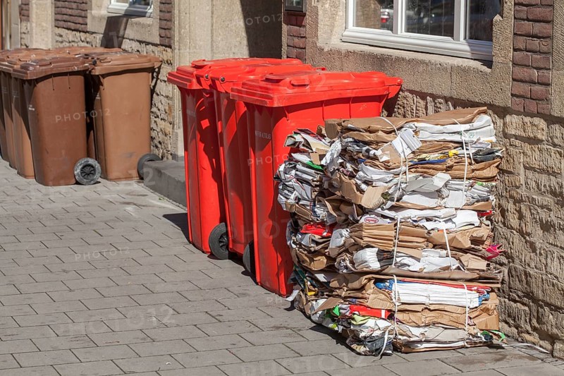Red bins for waste glass and stacks of waste paper