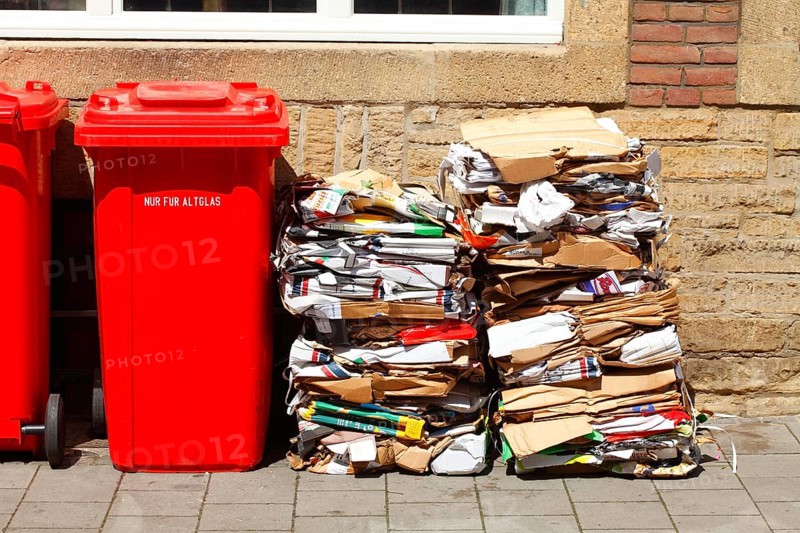 Red bins for waste glass and stacks of waste paper