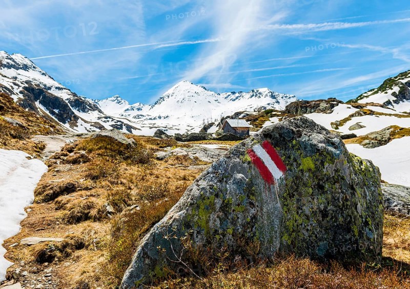 Red and white sign painted on rock marking hiking trail
