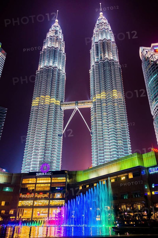 Lighted Petronas Towers with multicolored fountain at night