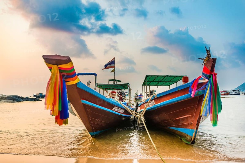 Moored colorful traditional long-tail boats on sandy beach