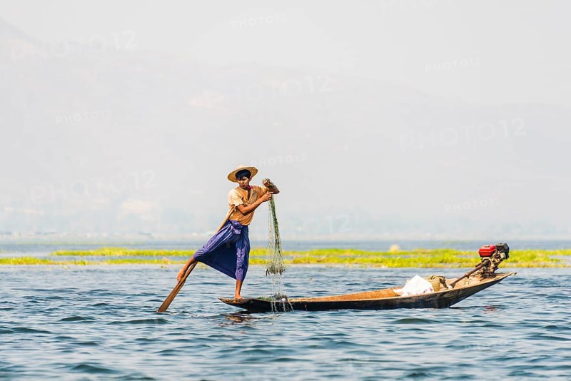 Local fishermen leg rowing on wooden boat